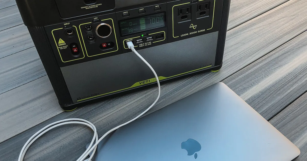 Portable power station charging a laptop on a wooden table during a power outage