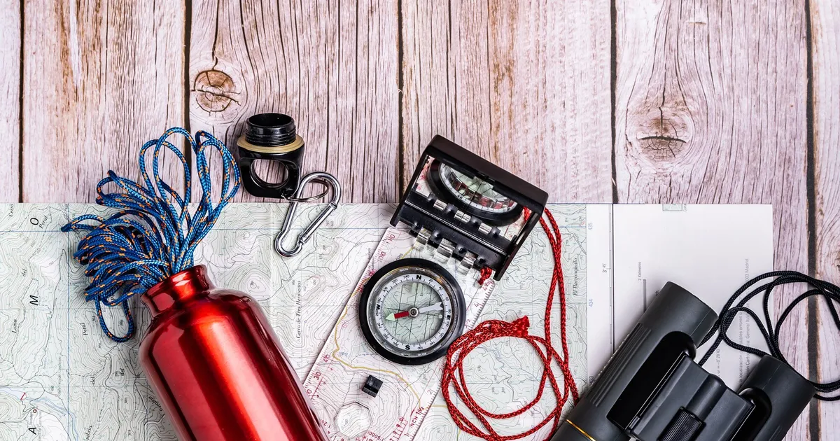 Survival gear and emergency supplies organized on a wooden table for building a 72-hour kit